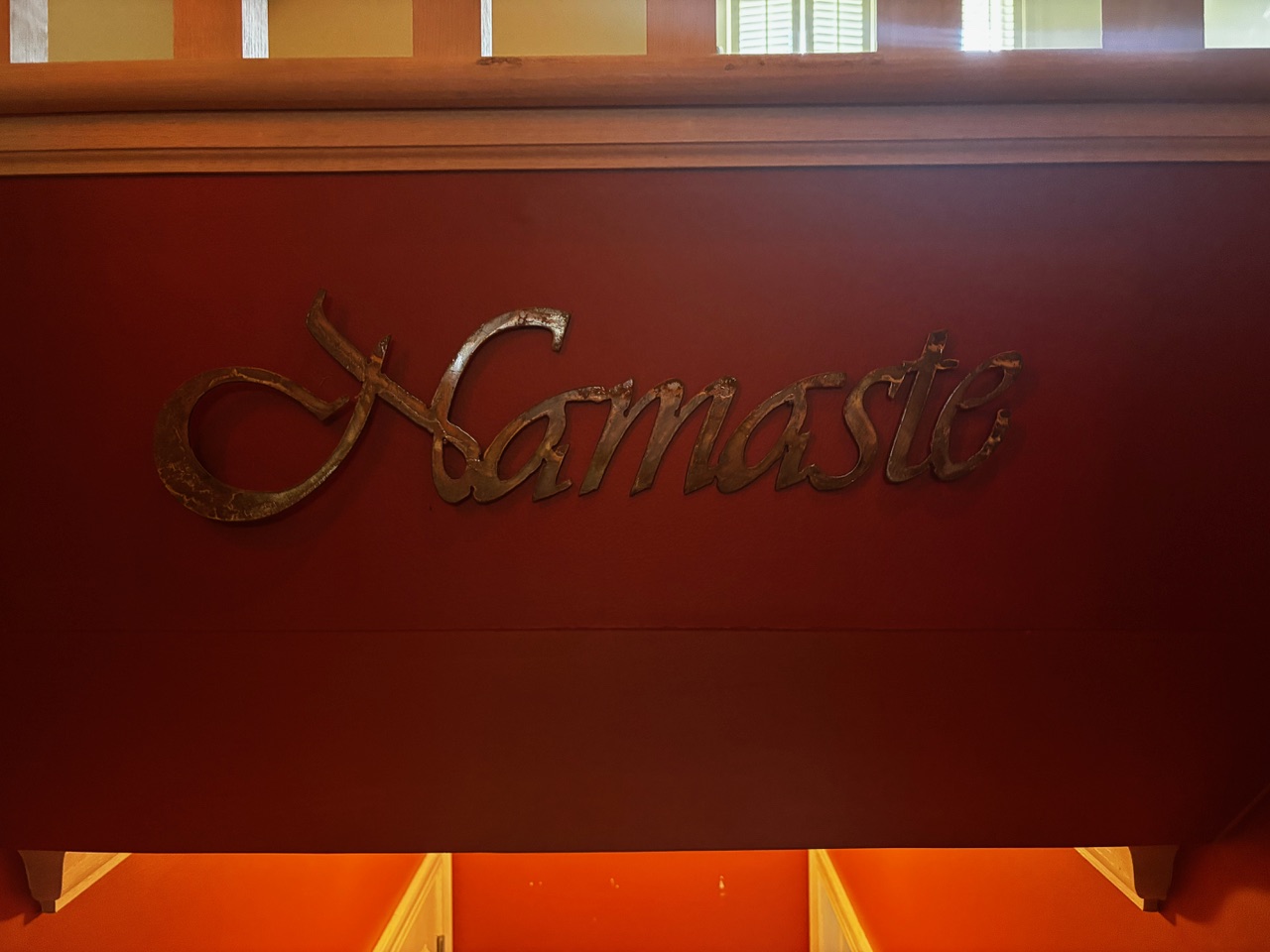 Metal Namaste wall art above the studio stairs